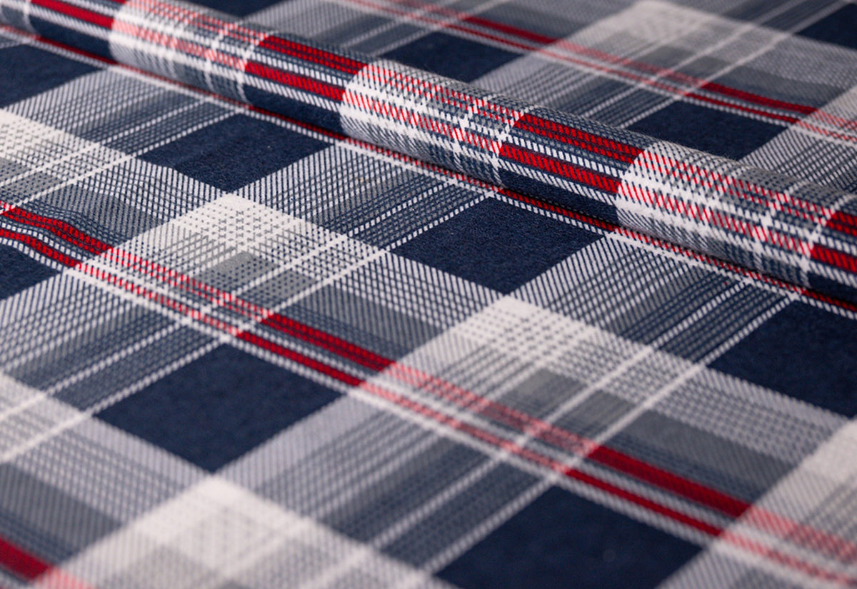 Housse en flanelle à carreaux bleus : tissu en flanelle enroulé à motif tartan bleu marine, gris clair et blanc avec de fines lignes rouges, détail du tissu photographié de biais